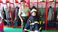 “我是小小消防員”主題活動，小朋友們在消防員叔叔的幫助下穿上消防衣。